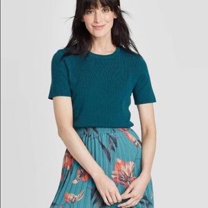 Short-sleeve teal crewneck pullover sweater.